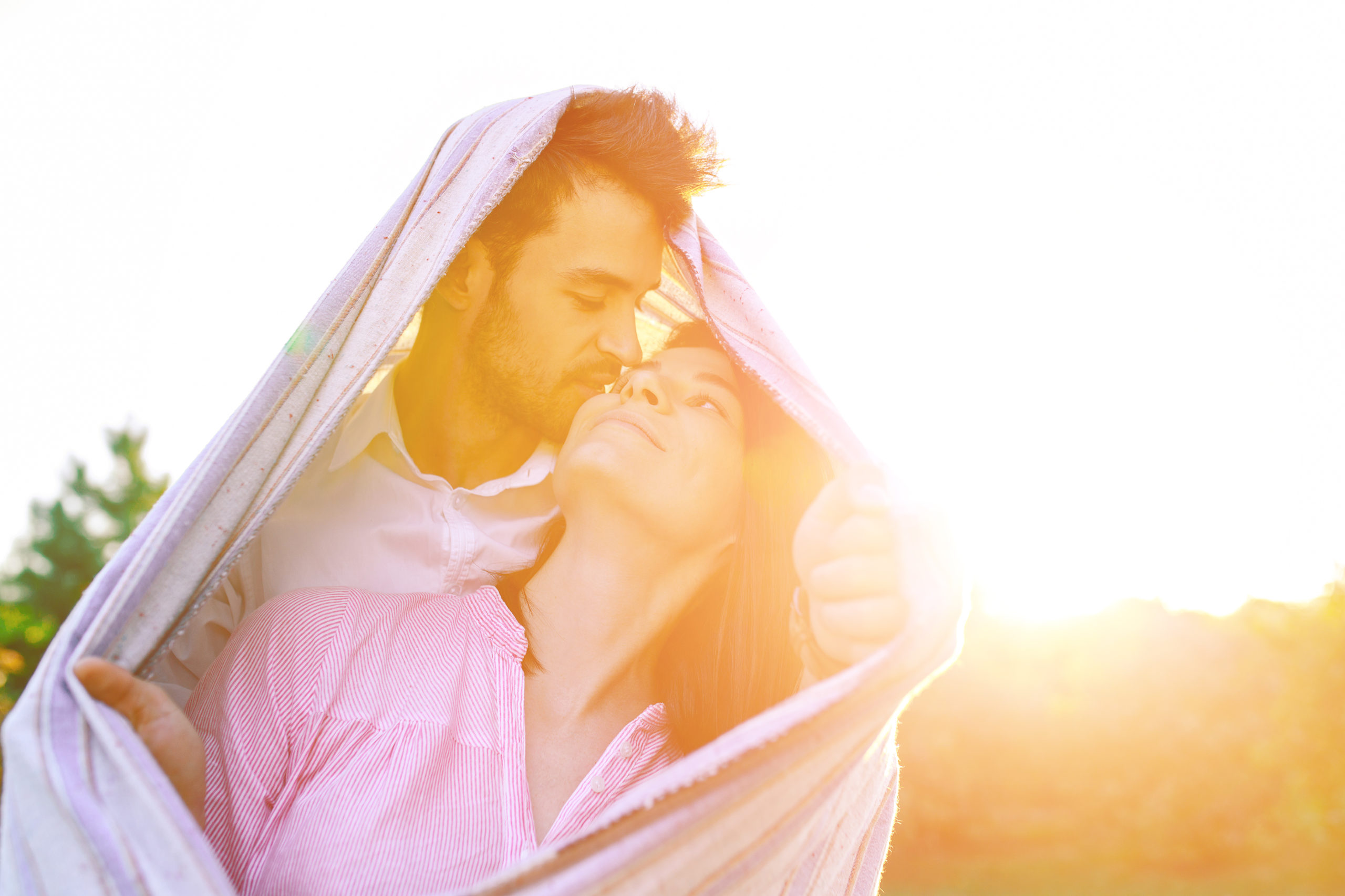 Happy couple portrait wrapped in a blanket enjoy each other in the rays of the sun outdoors